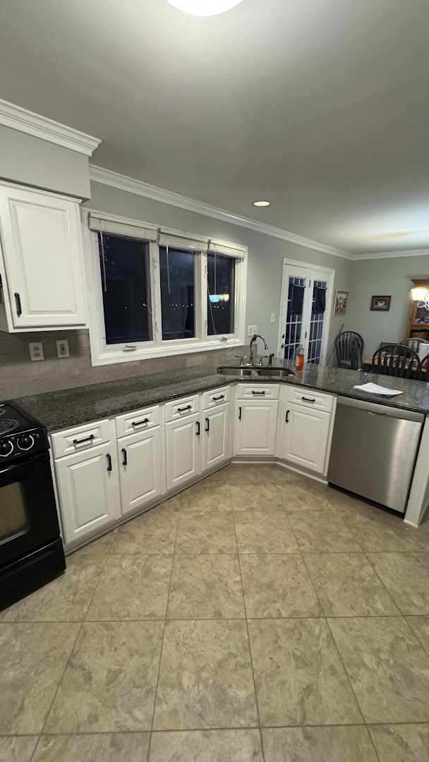 White kitchen cabinets with an island, sink, and stainless steel dishwasher