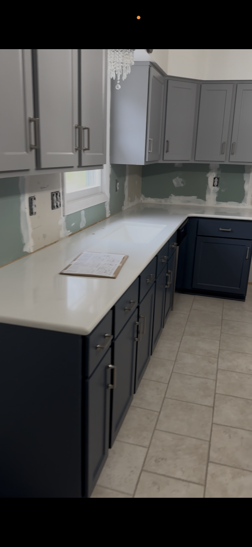 Kitchen renovation in progress with gray upper and navy lower cabinets