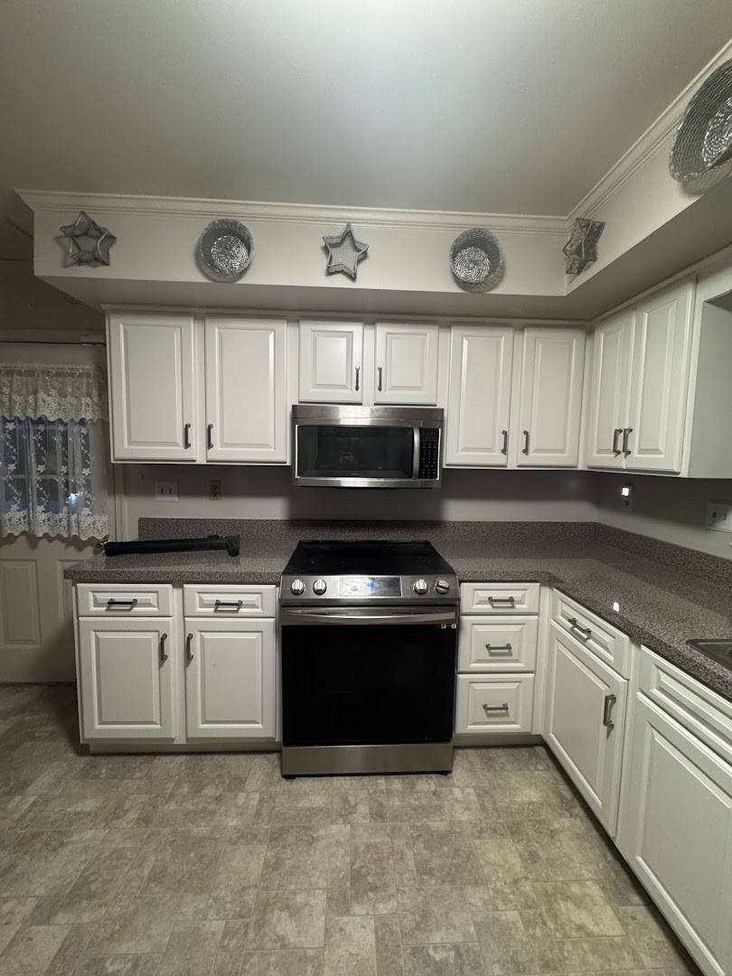 White raised-panel kitchen cabinets with a range and microwave
